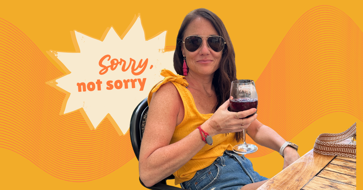 Kim Bode relaxes on a patio with a glass of iced wine in her hand. A speech bubble says, "Sorry, not sorry."